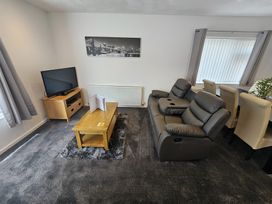 A living room with a television, coffee table, and reclining sofa at 58 Clifton Rise