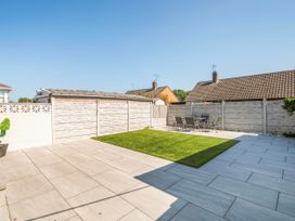 A garden with grass and paving stones at 58 Clifton Rise Abergele