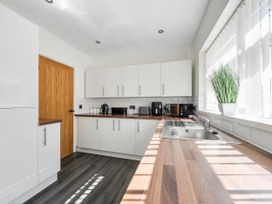 A kitchen with cabinets, a sink, and appliances at 58 Clifton Rise in Abergele