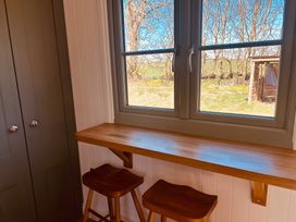 An indoor seating area with a table and stools at Y Nyth