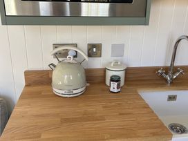 A kitchen with a kettle and jars on a wooden countertop at Y Nyth 