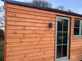 A wooden cabin exterior with a door and window at Y Nyth