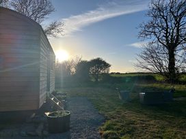 A wooden structure beside a gravel pathway with chairs at Y Nyth in 