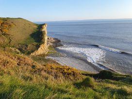 A cliff overlooking the sea with rocks and grass at Y Nyth in 