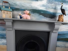 A mantle with a house decoration and plush toys at Lil Nauti