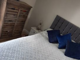 A bedroom with a bed, cushions, bedside table, lamp, and dresser at Lil Nauti