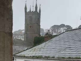 A church tower with a clock and surrounding roofs and trees at Lil Nauti