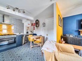 A kitchen and living area with a table and chairs at Lil Nauti in Fowey