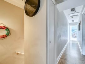 A hallway with a clock and life ring at Lil Nauti Fowey