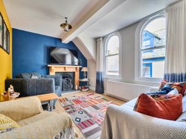 A living room with a television and sofa at Lil Nauti in Fowey