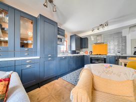 A kitchen featuring cabinetry, countertop, stove and dining area at Lil Nauti in Fowey