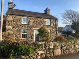A stone house with a wall and plants at Bwthyn Nain in 
