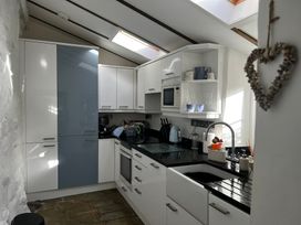 A kitchen with cabinets, sink, microwave, and utensils at Bwthyn Nain in 