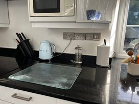 A kitchen with a kettle, microwave, and glass chopping board at Bwthyn Nain