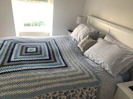 A bedroom with a bed covered in a blanket and pillows at Bwthyn Nain