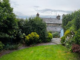 A garden with greenery and a house in the background at Bwthyn Nain 