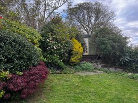 A garden with various bushes, flowers, and a garden shed at Bwthyn Nain 