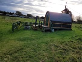 A hut with a wooden deck and fence in an outdoor area at St Austell Glamping