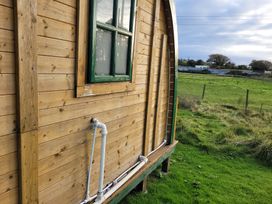 A wooden cabin exterior with a window and water pipe at St Austell Glamping
