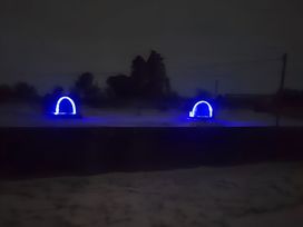 Two blue light structures in a dark outdoor area at St Austell Glamping