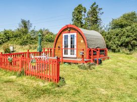 A glamping pod with a red fence and a green umbrella at St Austell Glamping in St Austell