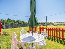 A table with chairs and an umbrella in an outdoor area at St Austell Glamping St Austell