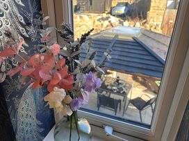 A window with artificial flowers and a view of outdoor furniture at an unknown property