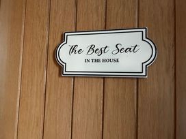 A sign reading The Best Seat IN THE HOUSE on wood paneling
