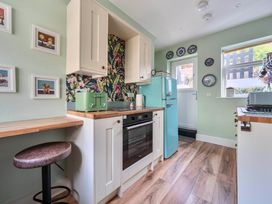 A kitchen with a fridge, oven, and bar stool at 20 Main Street in Heysham