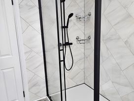 A shower with glass door and tiled walls at 140 Finchley Road