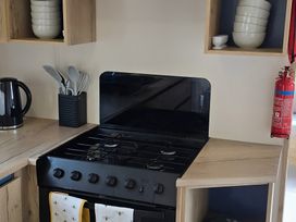 A kitchen countertop with a stove, kettle, and utensil holder at Caravan in 
