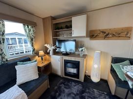 A living room with a sofa, television, and shelves at the property in location
