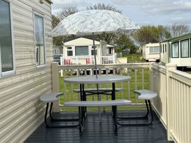 A table with umbrella and seating on a patio outside a caravan at 