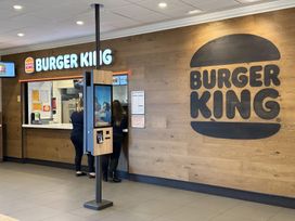 A Burger King ordering counter with a kiosk at a restaurant