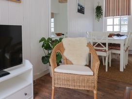 A living room with a television and a rattan chair at 1 The Old Posthouse in Lyme Regis