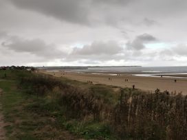 A beach scene with people walking along the shore at 38A Bridlington
