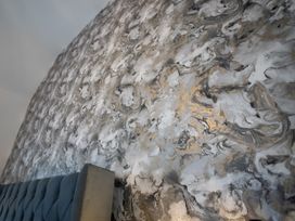 A bedroom with a patterned wall and a tufted headboard at The Shearling in Morpeth