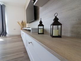 A living room with a tv and lanterns on a shelf at The Newland in Morpeth
