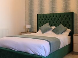 A bedroom with a green headboard and white bedding at The Newland in Morpeth