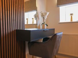 A desk with a chair and a flower vase under a window at The Newland in Morpeth