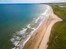 An aerial view of a beach meeting the ocean with waves at The Newland in Morpeth