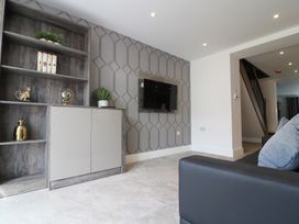 A living room with a shelf, TV, and decorative items at The Gavel in Morpeth