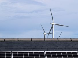 Wind turbines visible above a roof with solar panels