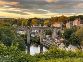A view of a bridge over a river with surrounding houses at Honeysuckle Lodge in Knaresborough