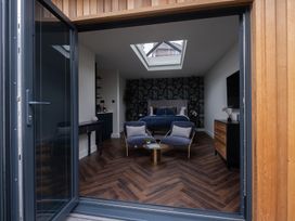A bedroom with a bed and two armchairs at Honeysuckle Lodge Knaresborough