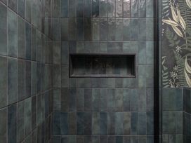 A shower area with green tiles and a niche at Honeysuckle Lodge in Knaresborough