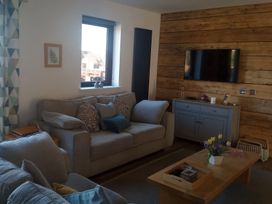 A living room with a couch, television, and coffee table at Gowrie Lodge in Blairgowrie