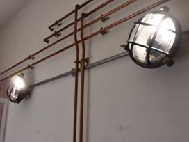 Light fixtures and copper pipes on a wall at Ty Llaeth in Carmarthen