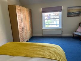 A bedroom with a wardrobe and a chair at Edal Court in Sheringham