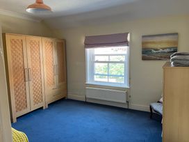 A bedroom with a wardrobe and window at Edal Court in Sheringham